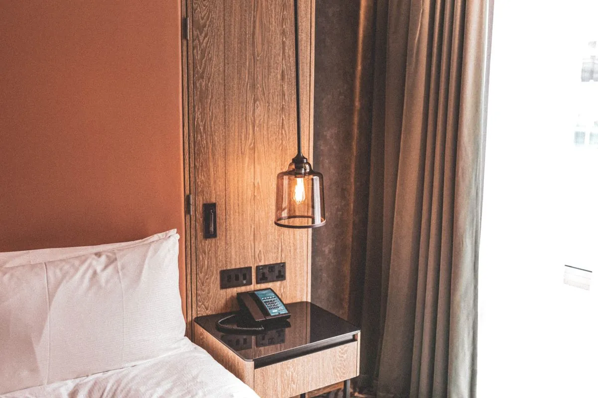 A bedroom with a warm pendant lamp and dark wood