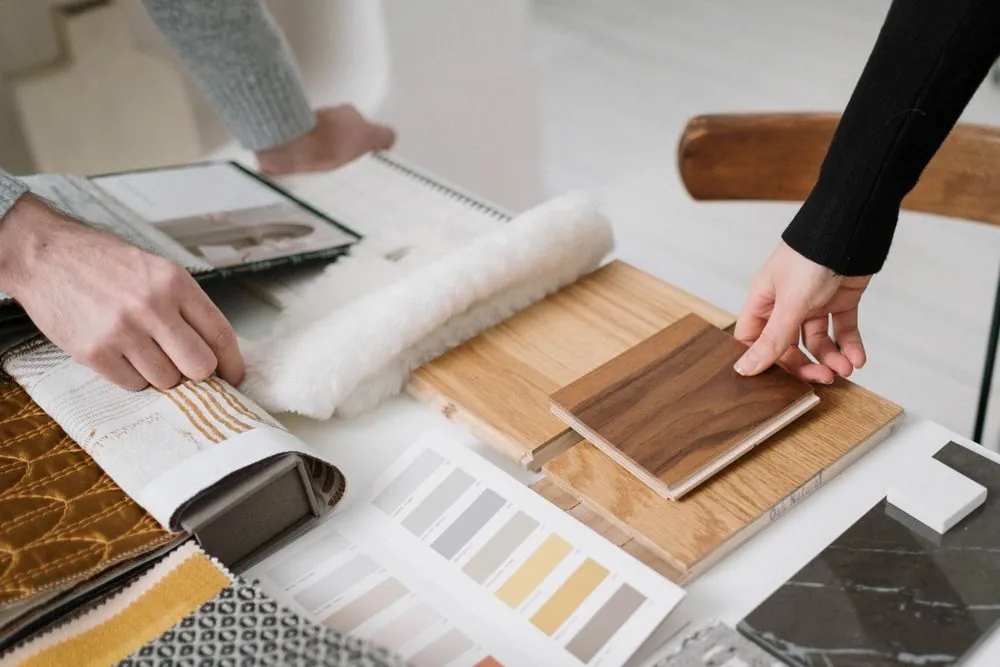 Hands laying out wood and fabric samples on a table